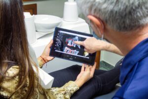 Photo by Quang Tri NGUYEN on Unsplash https://unsplash.com/photos/woman-in-blue-denim-jeans-holding-black-tablet-computer-T-iifFLk3KU - dentist reviewing imaging with a patient