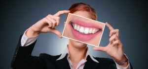 https://pixabay.com/photos/woman-smile-teeth-health-tooth-3498849/ woman holding up a bright smile card in front of her face