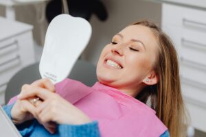 Woman smiling at her teeth and reflection after a dental procedure www.kaboompics.com: https://www.pexels.com/photo/smiling-woman-in-dentist-chair-looking-in-mirror-6627574/ 